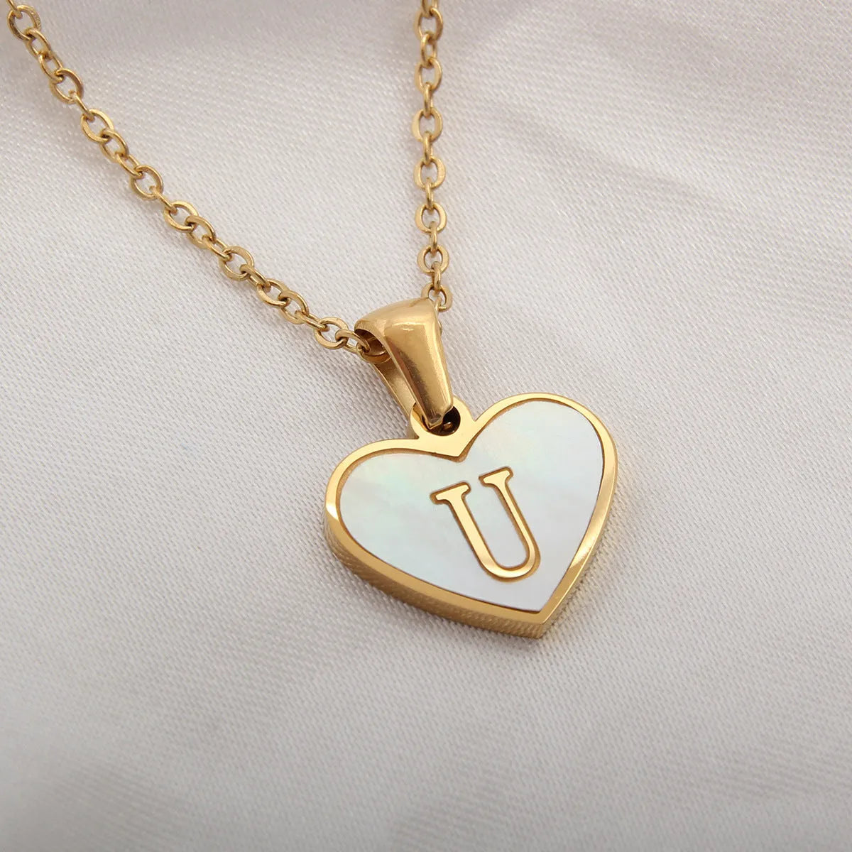 Gold-plated heart necklace with white shell pendant showing letter personalisation option