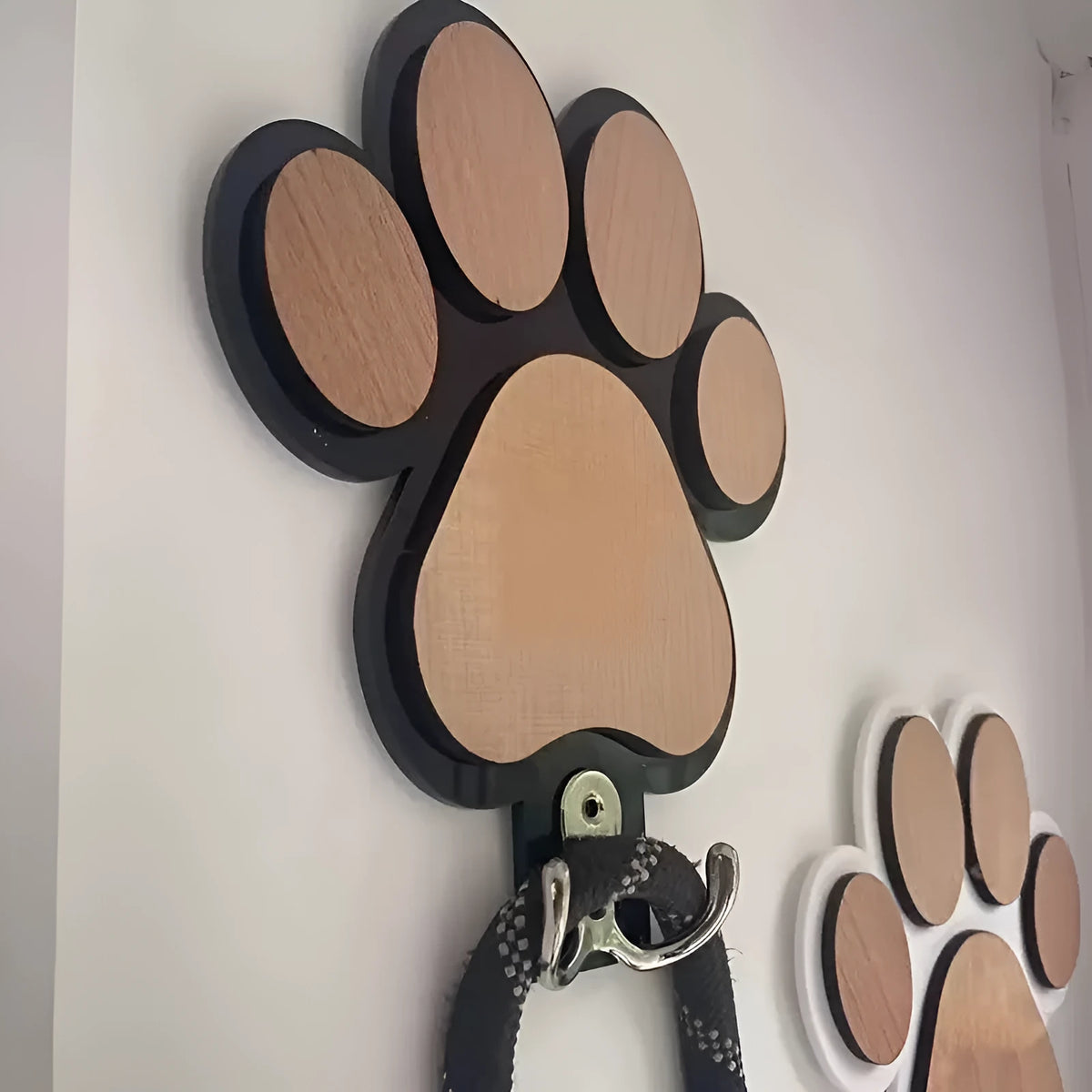 Black wooden wall hook shaped like a paw print foot on a white wall