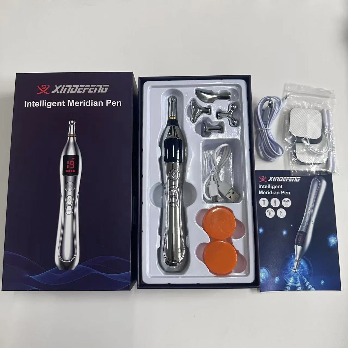 Rechargeable charging acupuncture pen with five massage heads and USB cable on a table.