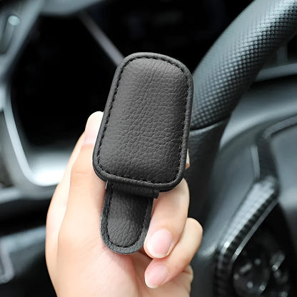 Car sunglasses holder clip with PU leather case attached to a sun visor.