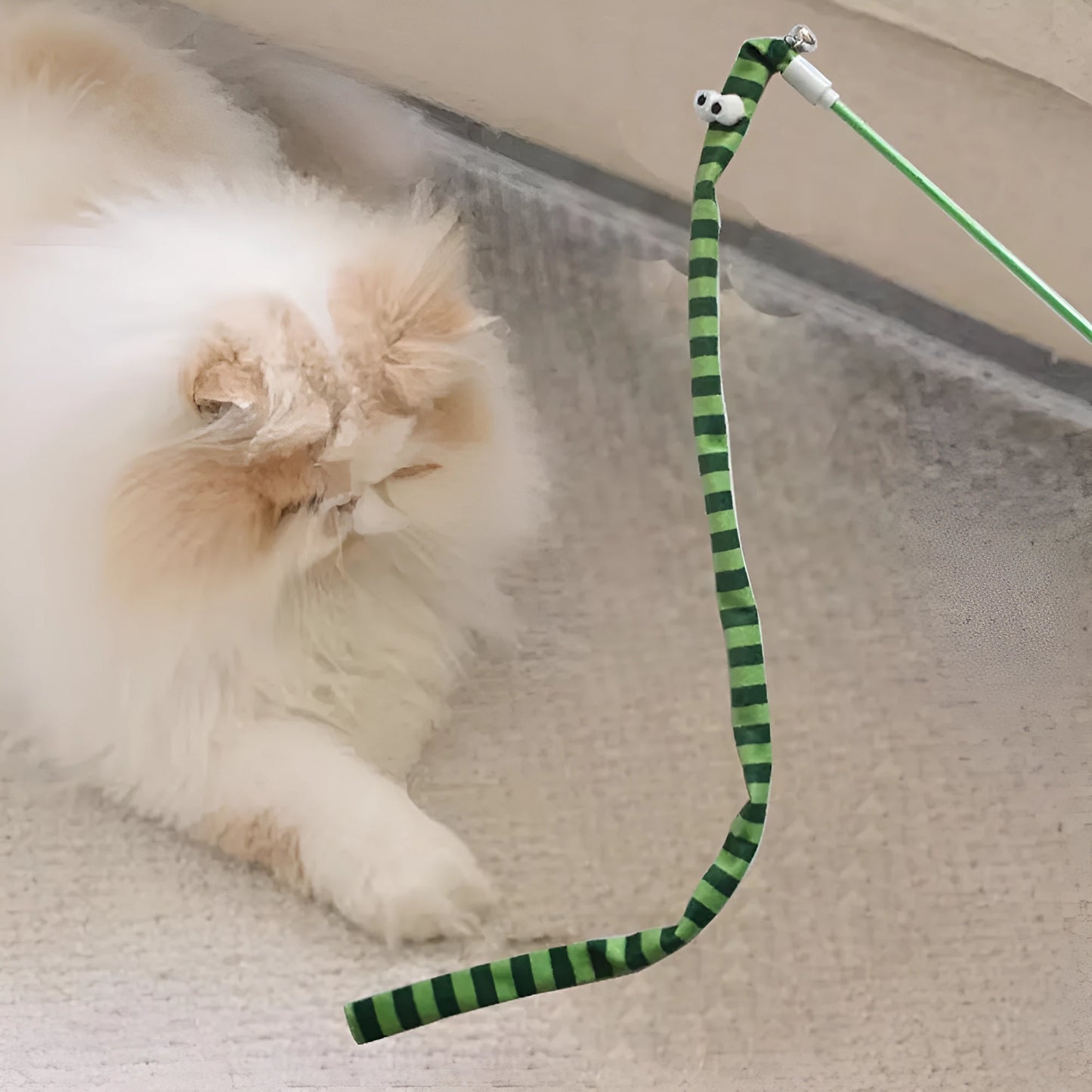 Interactive cat wand toy with a polycarbonate handle and a long green plush strip with a bell.