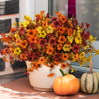 Artificial flower bouquet in autumn colours of red, yellow, and orange made from plastic and silk.