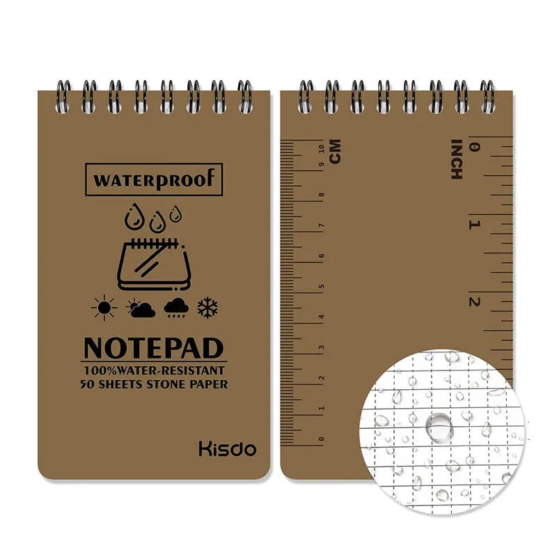 Spiral-bound waterproof notepad in camouflage colour, open on a wooden surface with a pen.