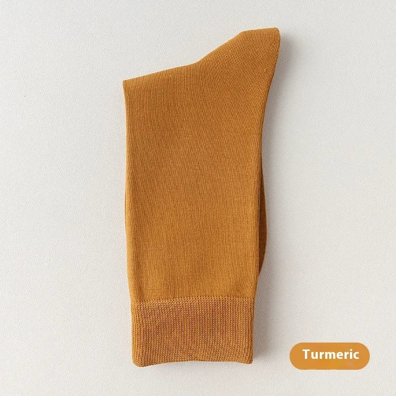 Pair of solid-colour men's mid-calf socks made from combed cotton on a wooden background