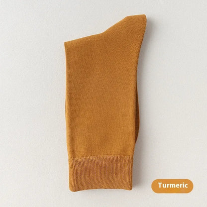 Pair of solid-colour men's mid-calf socks made from combed cotton on a wooden background