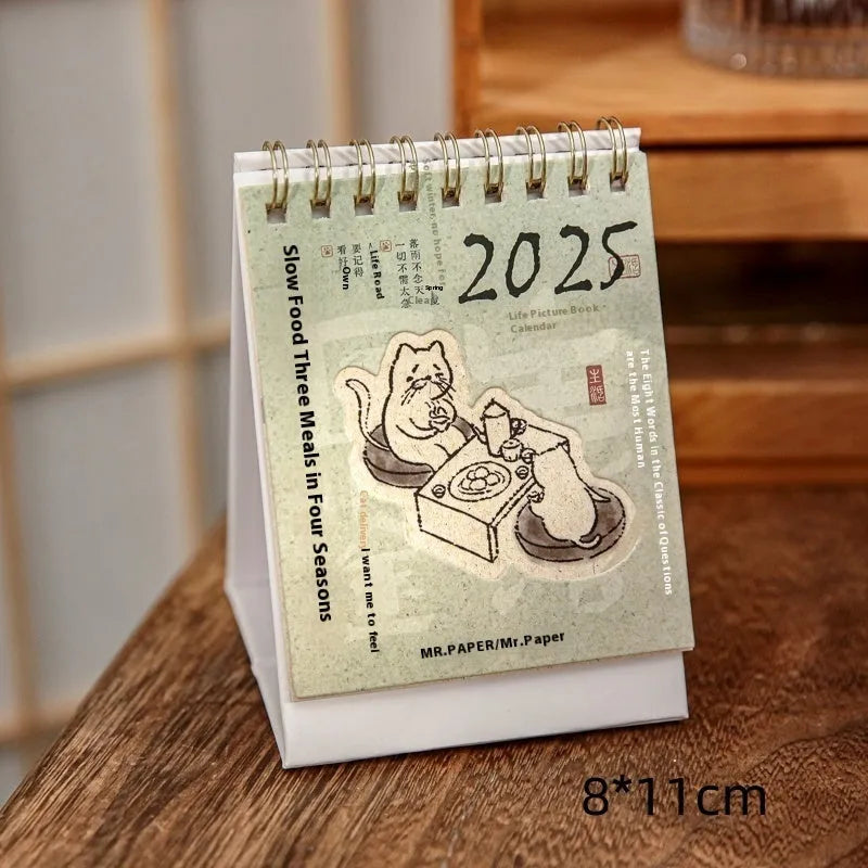 Set of four different themed 2025 mini paper desk calendars on a desk.
