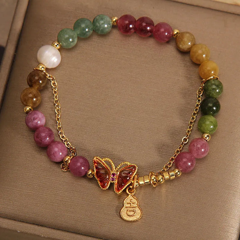 Close-up of a jade green tourmaline butterfly gourd charm on a brown agate bracelet for women.