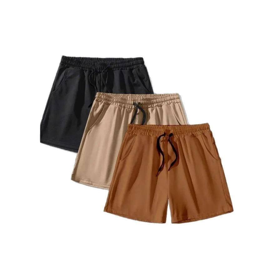 Three pairs of men's solid colour loose-fit drawstring shorts in black, khaki, and light brown laid flat.