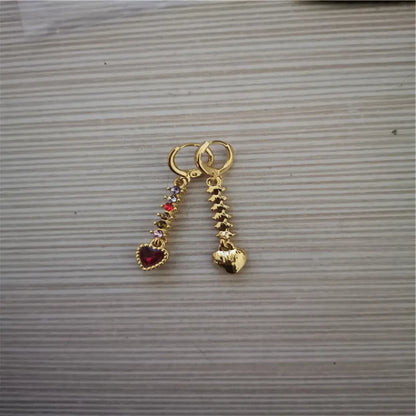 A pair of small gold-coloured heart-shaped alloy earrings on a plain background.