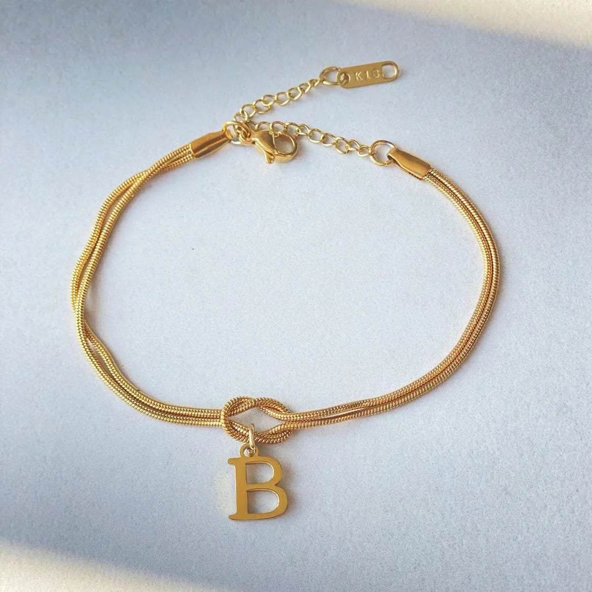 Elegant letter charm bracelets for women in gold and silver tones, featuring a delicate snake chain design and personalised letter charms.