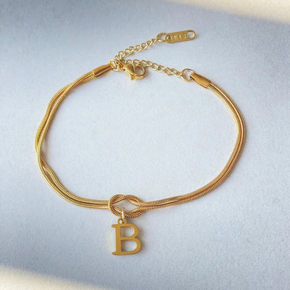 Elegant letter charm bracelets for women in gold and silver tones, featuring a delicate snake chain design and personalised letter charms.