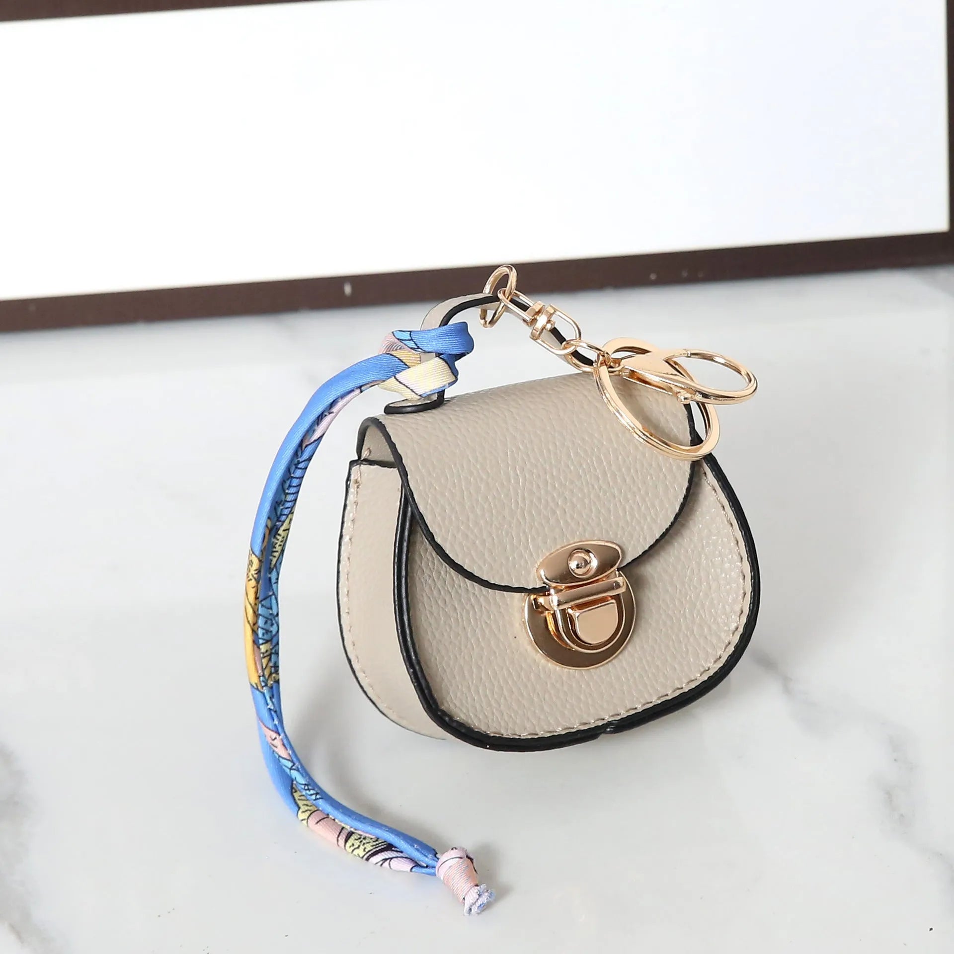 Solid colour PVC coin purse keychain shown in saddle bag black, orange, brown, red, grey, and pink.