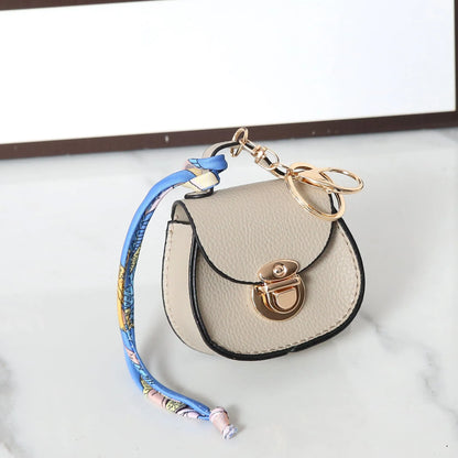 Solid colour PVC coin purse keychain shown in saddle bag black, orange, brown, red, grey, and pink.