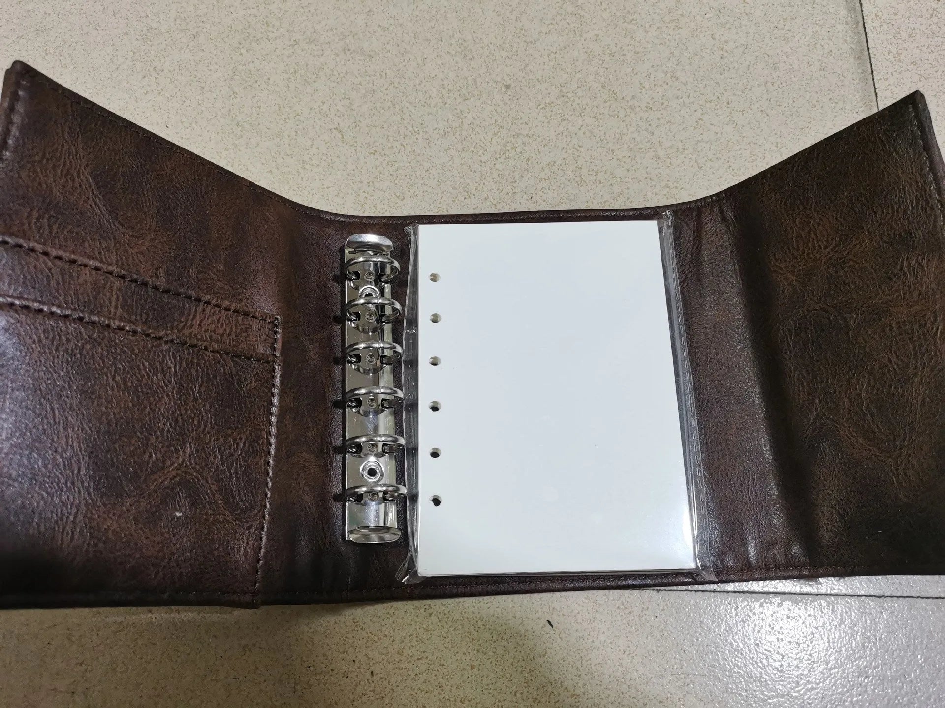 Brown A7 loose-leaf notebook with PU cover and retro buckle design, shown open.