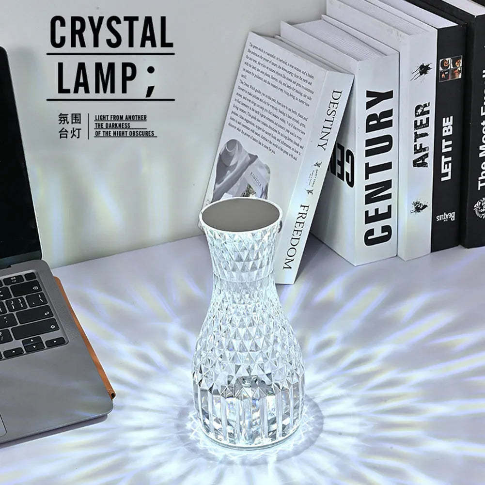 Vase-shaped crystal table lamp with remote control on a bedside table, showing diamond-like glow and USB charging port.