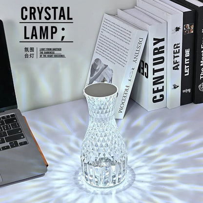 Vase-shaped crystal table lamp with remote control on a bedside table, showing diamond-like glow and USB charging port.