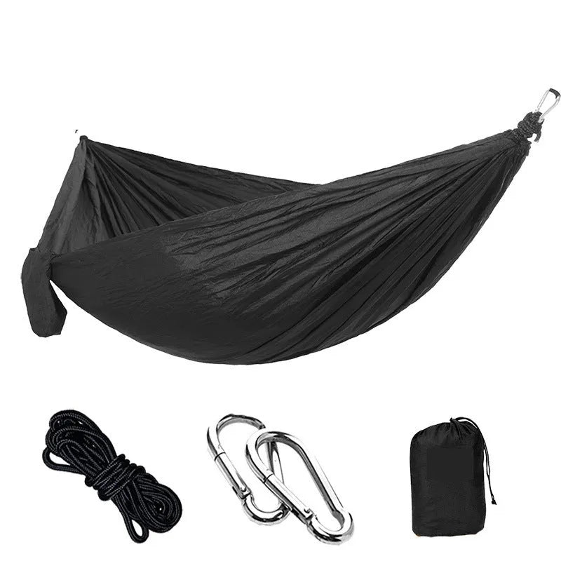 Parachute cloth double camping hammock in chosen colour, with black buckles and round ropes on a tree.