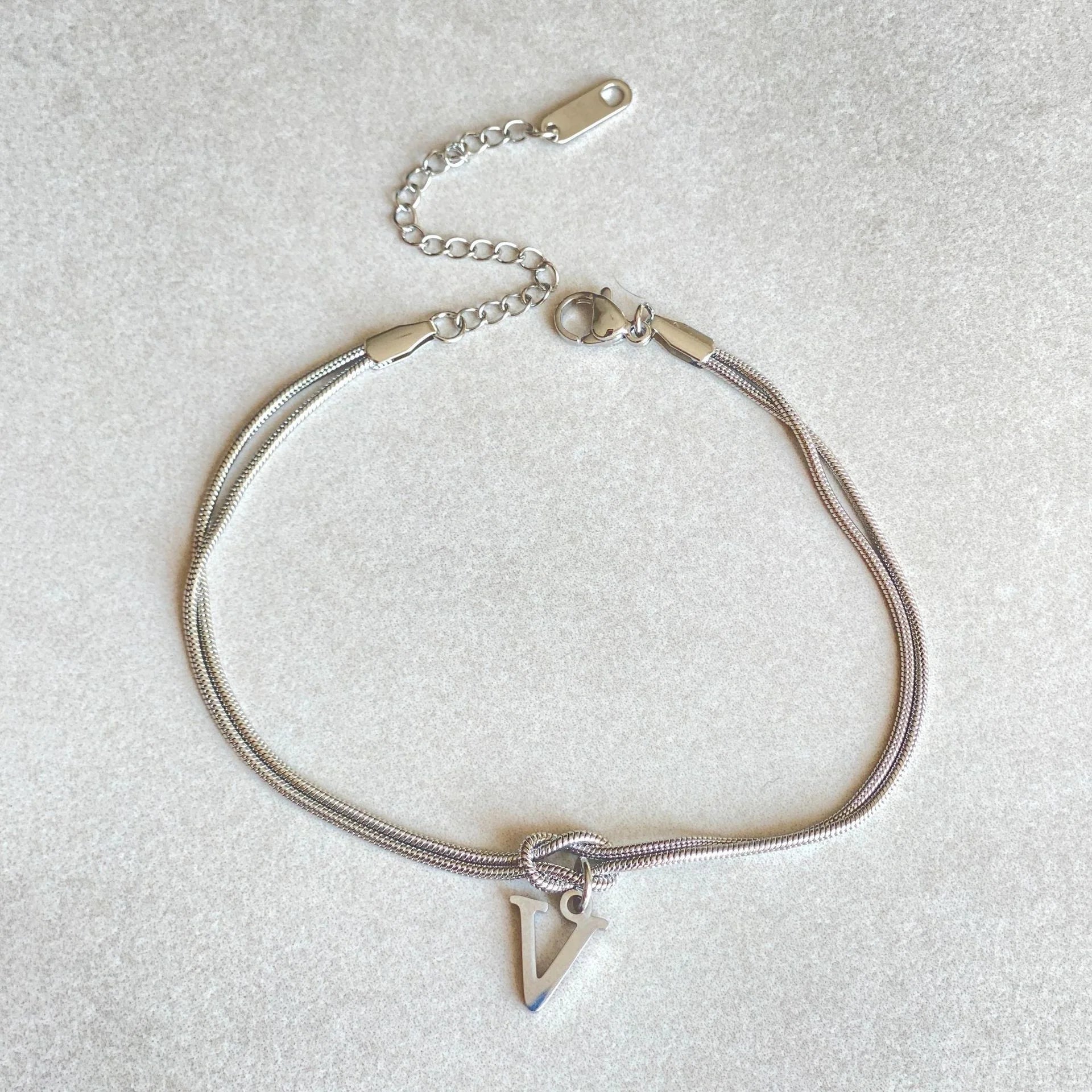 Elegant letter charm bracelets for women in gold and silver tones, featuring a delicate snake chain design and personalised letter charms.
