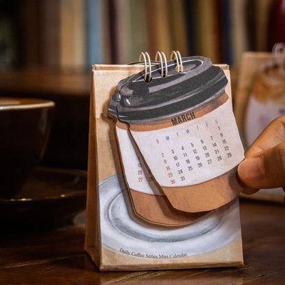 Set of four different themed 2025 mini paper desk calendars on a desk.