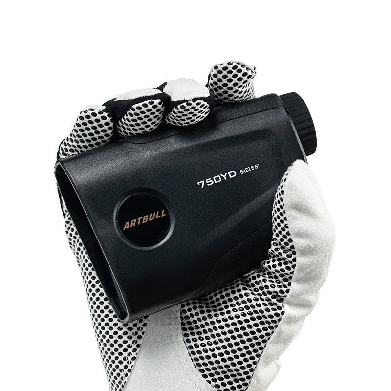 Black golf laser rangefinder with LCD display showing yardage, placed on a green golf towel.