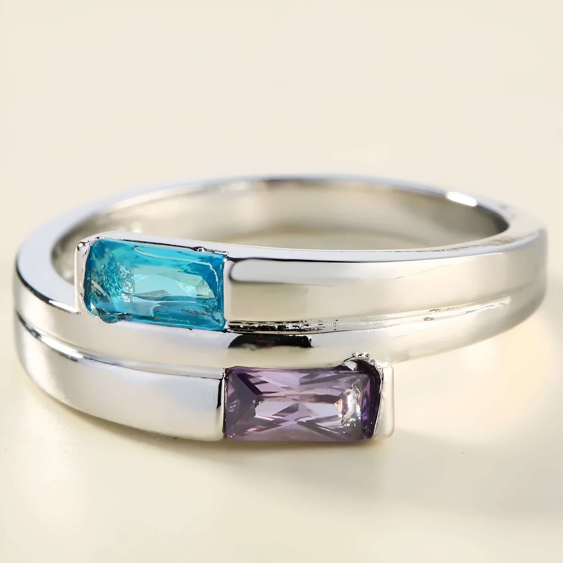 Silver coloured copper electroplated ring with a central zircon stone, shown on a finger.