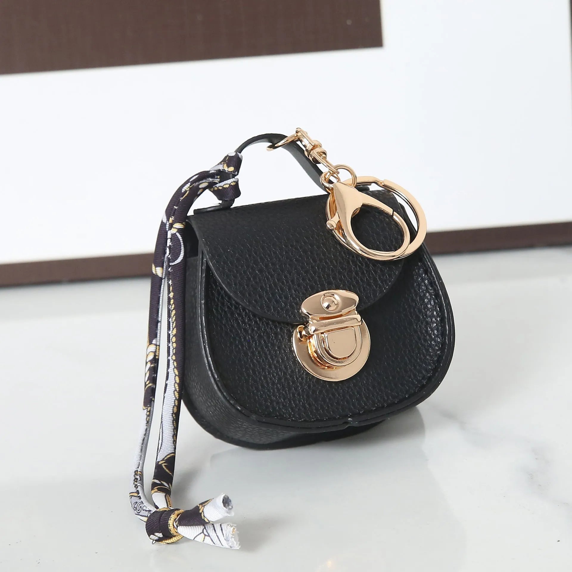 Solid colour PVC coin purse keychain shown in saddle bag black, orange, brown, red, grey, and pink.