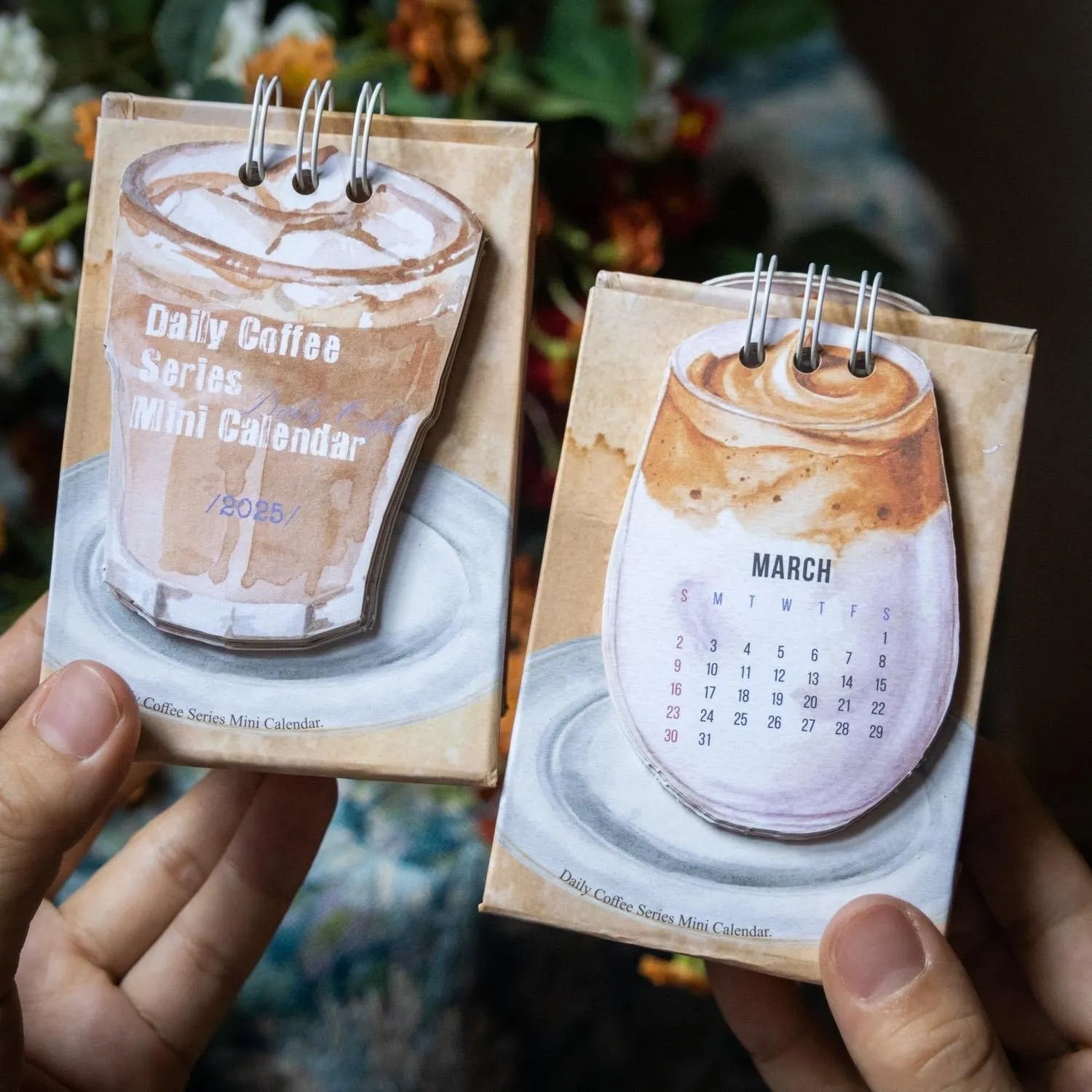 Set of four different themed 2025 mini paper desk calendars on a desk.