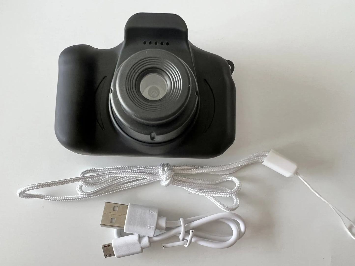 X2 HD mini digital camera for kids in silicone case with lanyard, shown capturing photo on 2-inch screen.