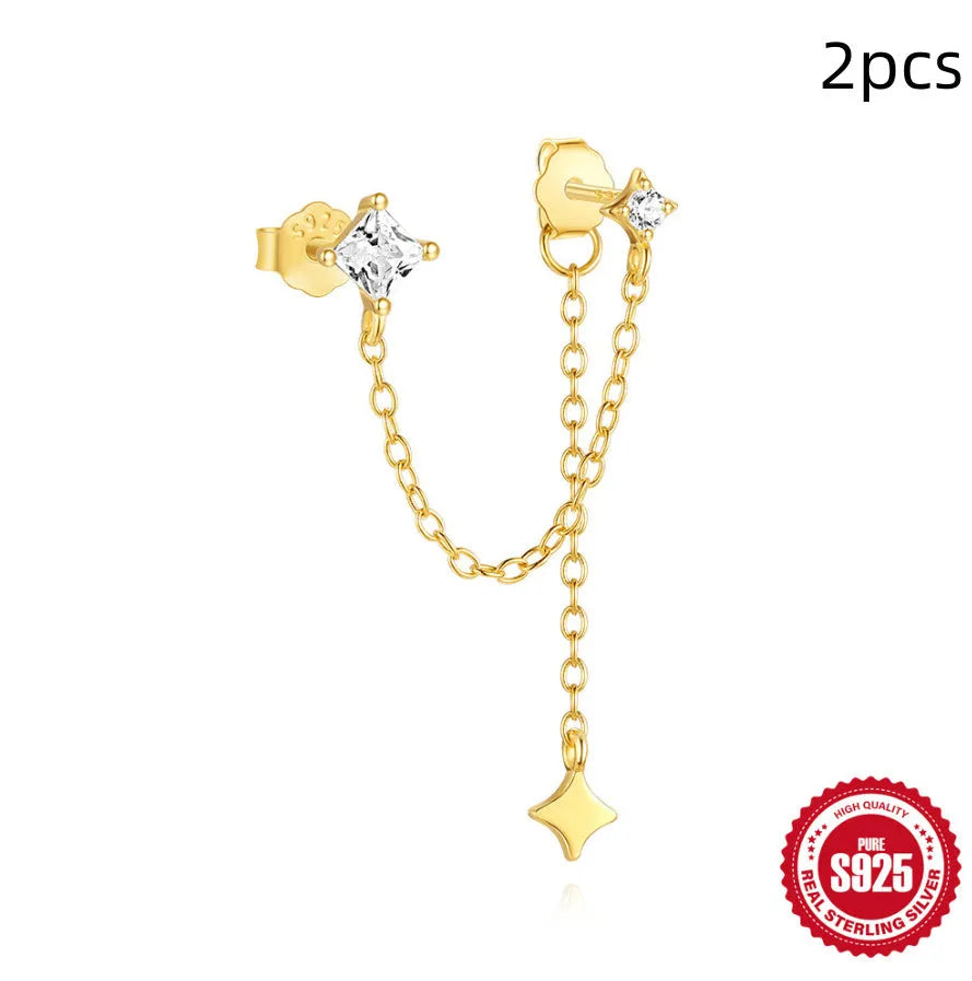 Close-up of a sterling silver double piercing chain stud earring with inlaid zircon stone in a golden colour.