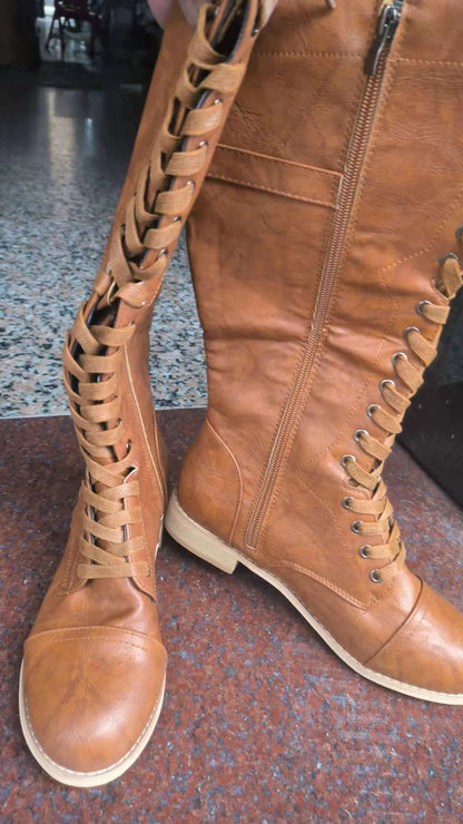 Women's black knight ankle boots with cross straps and buckles over lace-up front.