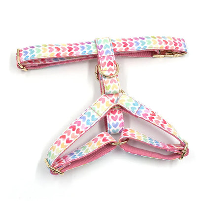 Pink dog harness with gold buckle and heart-shaped stones on a chest and back strap.