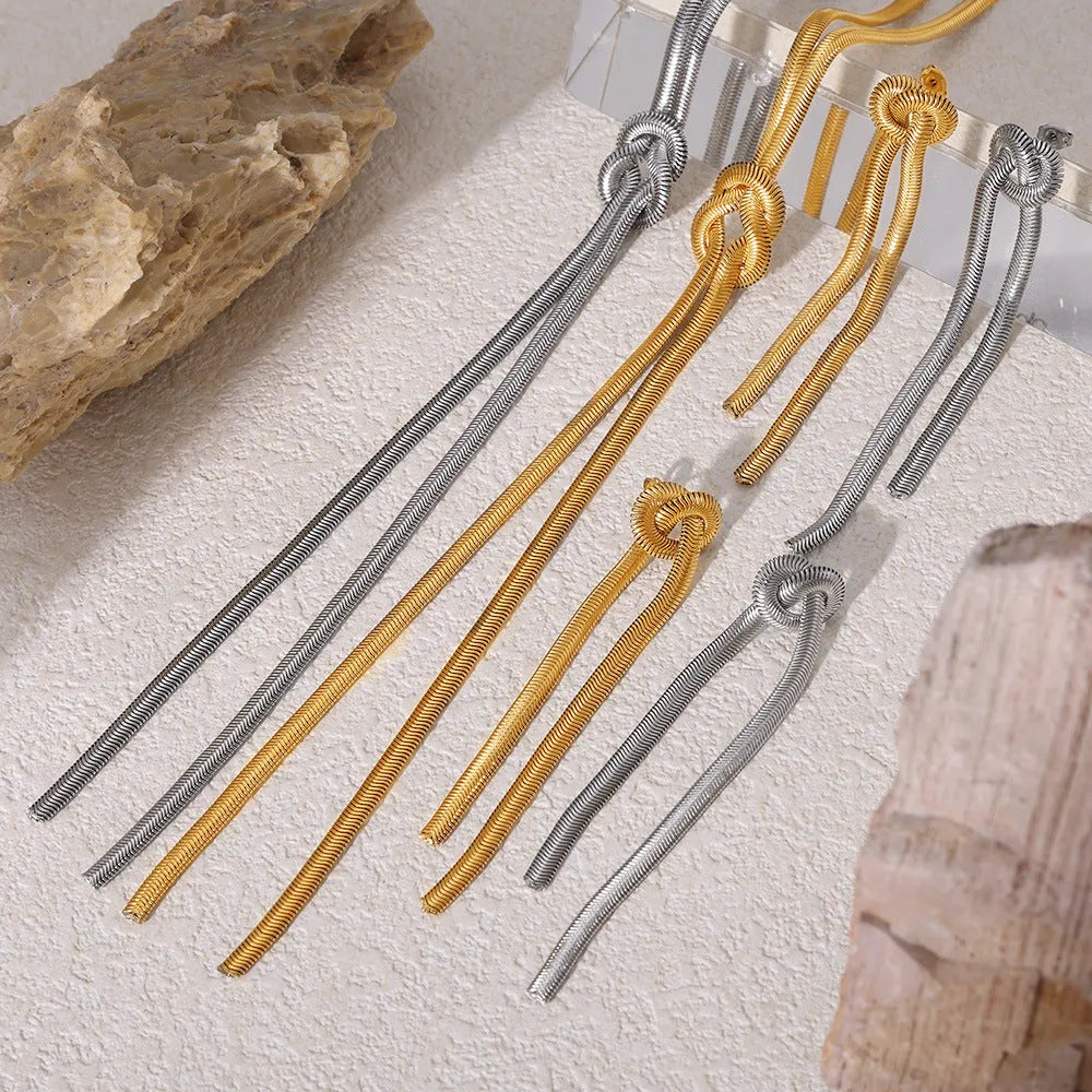 Gold electroplated titanium steel necklace with snake chain and knotted tassel pendant, shown with matching earrings.