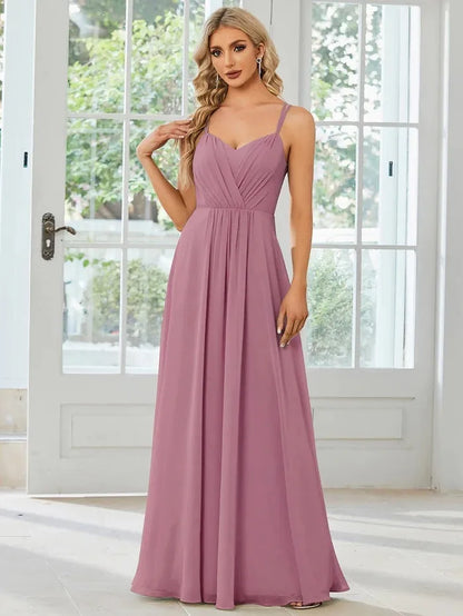 Woman wearing a light green sleeveless dress with a long pleated A-line skirt.