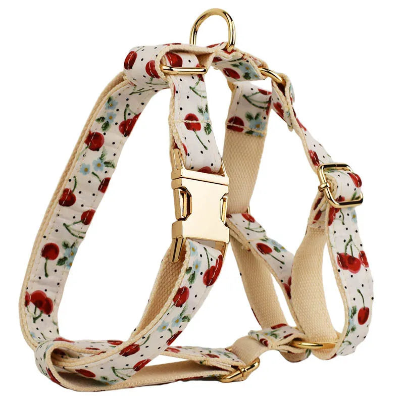 Red cherry printed dog collar with light gold buckle and matching leash, bow, vest and poop bag holder set