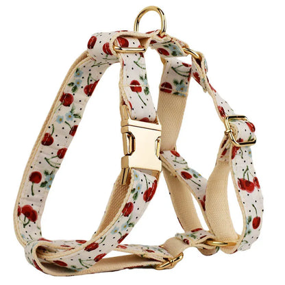 Red cherry printed dog collar with light gold buckle and matching leash, bow, vest and poop bag holder set
