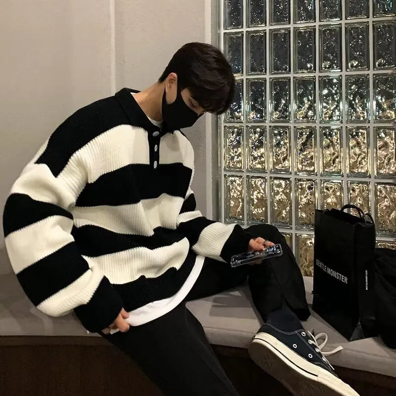 Man wearing a loose grey and black striped long sleeve pullover sweater.