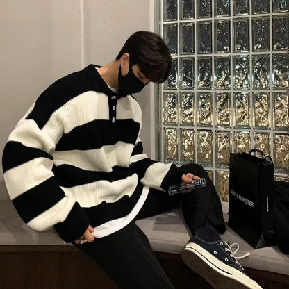Man wearing a loose grey and black striped long sleeve pullover sweater.