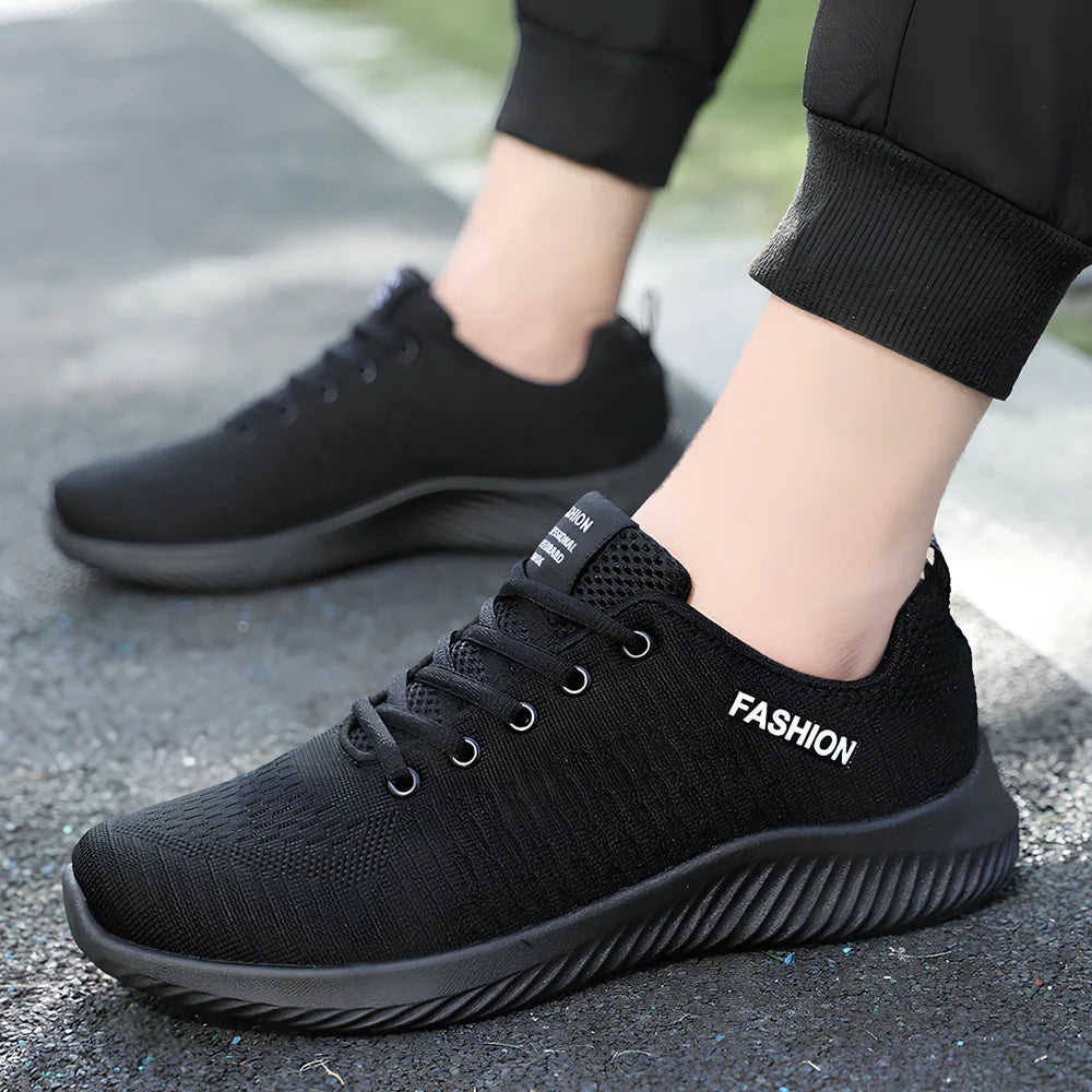 Men's black mesh sports shoes with red accent details and flexible PVC sole construction