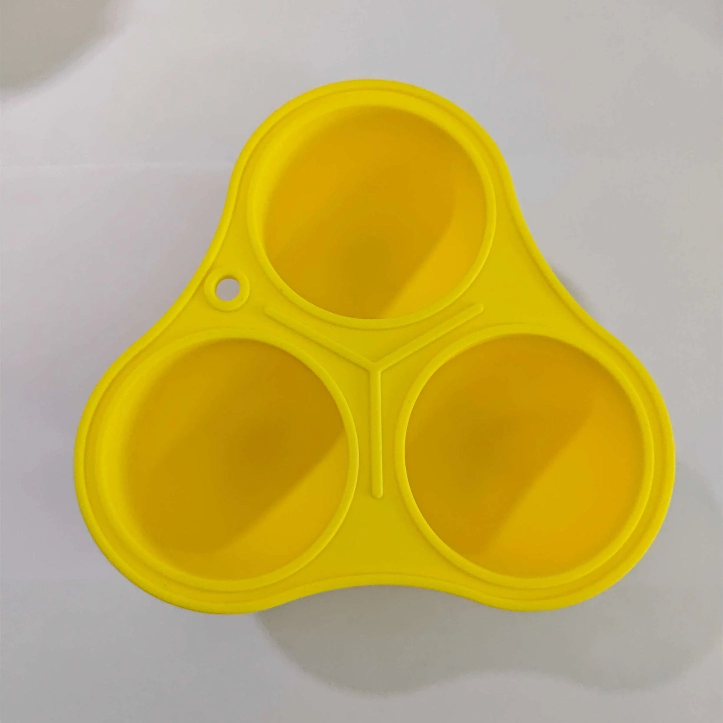 Yellow silicone pet slow feeding ball with treat-dispensing moulded interior for dental cleaning