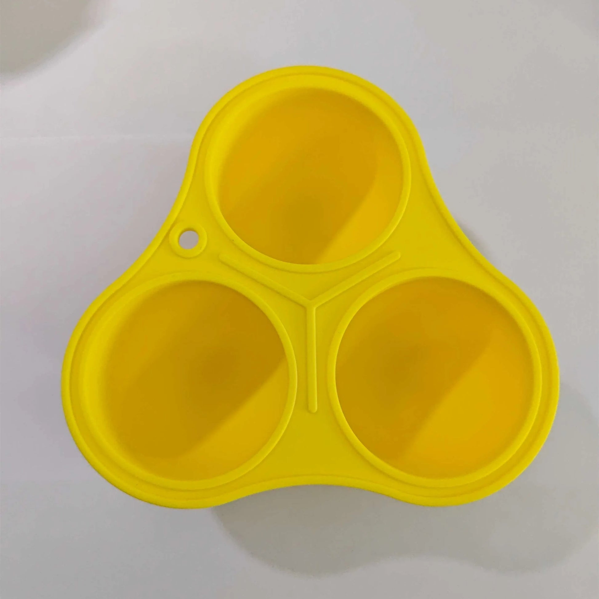 Yellow silicone pet slow feeding ball with treat-dispensing moulded interior for dental cleaning