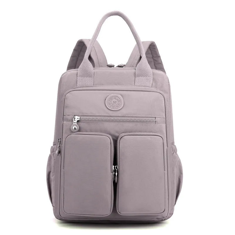 Women's waterproof nylon travel backpack in grey, showing front external pocket and organisational interior.