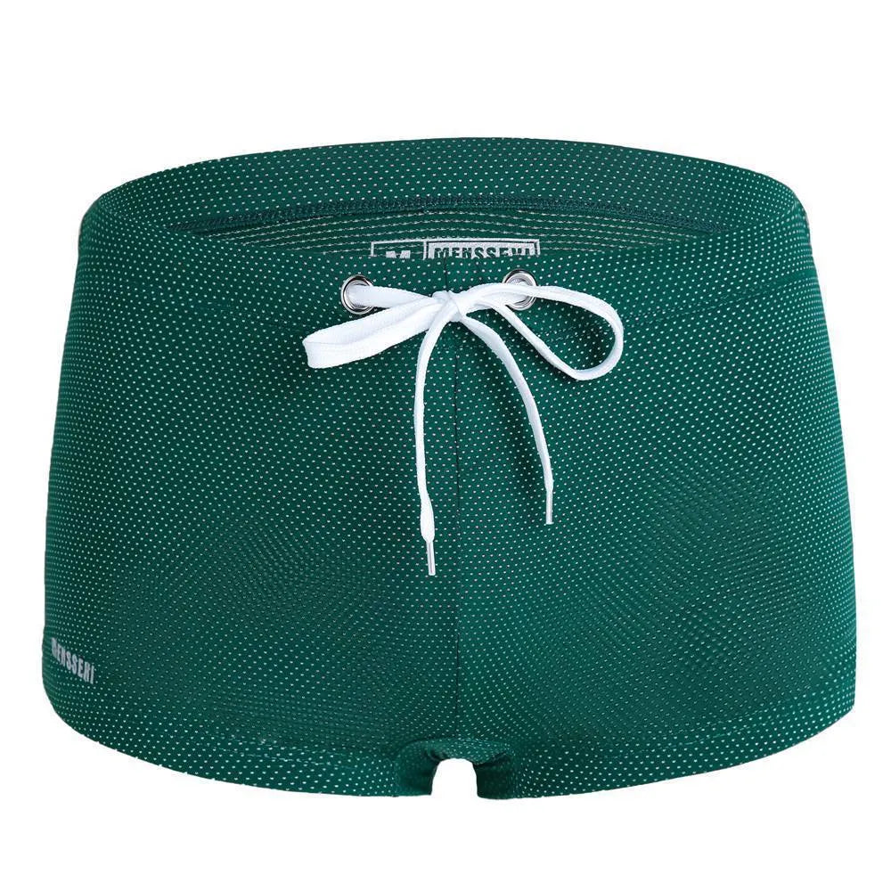 Men's low waist swim trunks in stretch nylon on a man, showing elastic waistband and boxer-style cut.