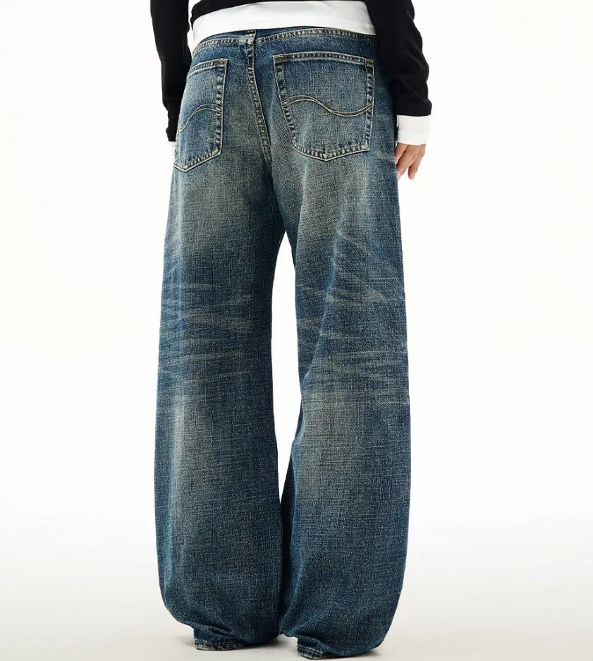 Men's wide leg mid waist jeans in dark blue denim with straight loose cut and distressed cat beard detail
