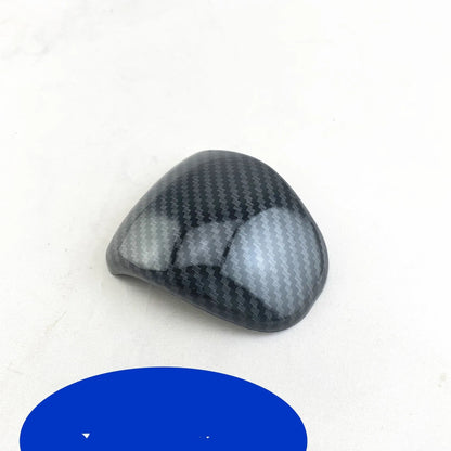 Black carbon fibre effect plastic cover for a car gear shift knob.
