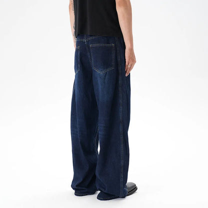 Dark blue distressed wide leg Machete jeans laid flat, showing washed denim texture.