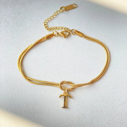 Elegant letter charm bracelets for women in gold and silver tones, featuring a delicate snake chain design and personalised letter charms.