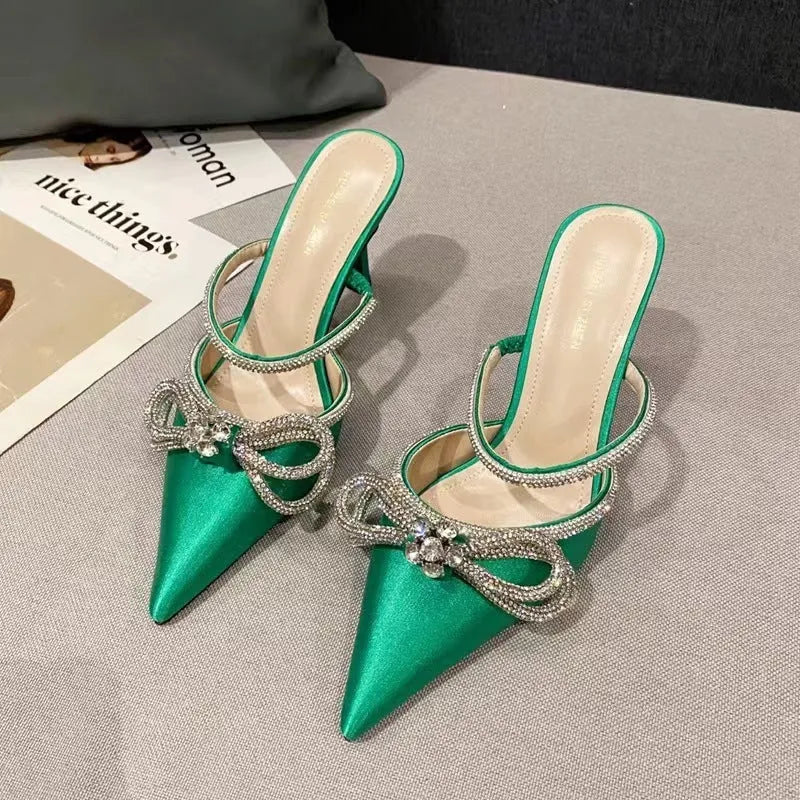 Women's black stiletto heel sandals with silk bandage ankle strap and buckle fastening on a pointed toe.