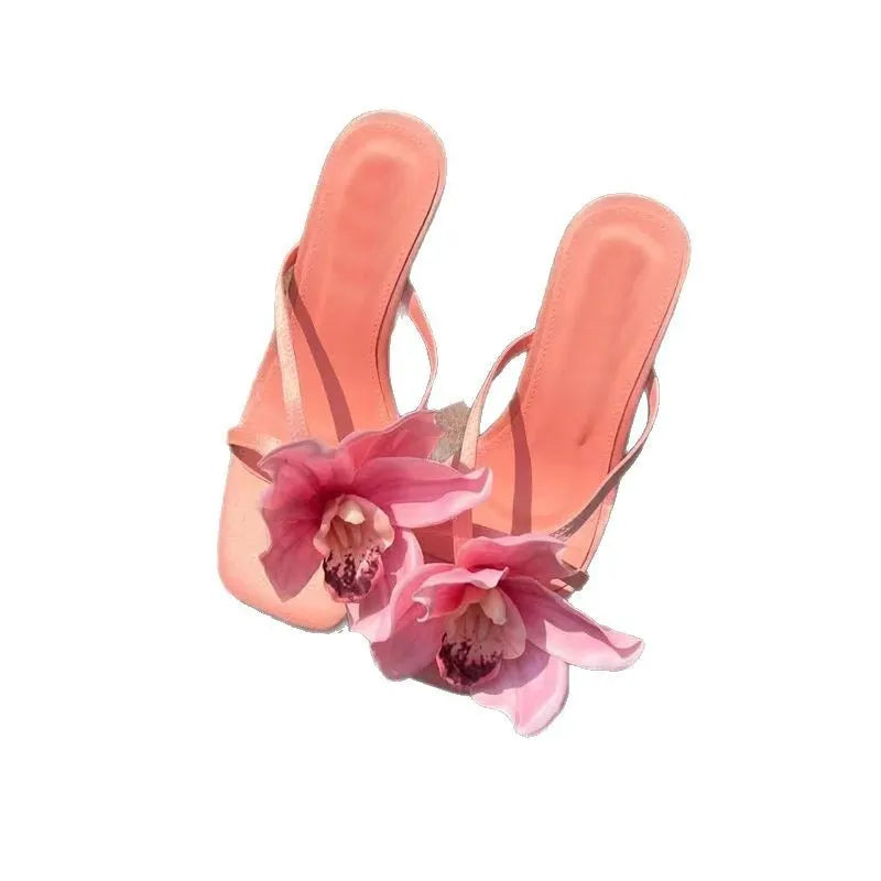 Pink women's sandals with a satin upper, artificial white Phalaenopsis flower, square toe, and a mid-height heel.