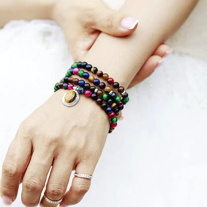 Coloured tiger-eye natural stone bead necklace and bracelet set with 108 gem-inlaid pendants on a dark background.