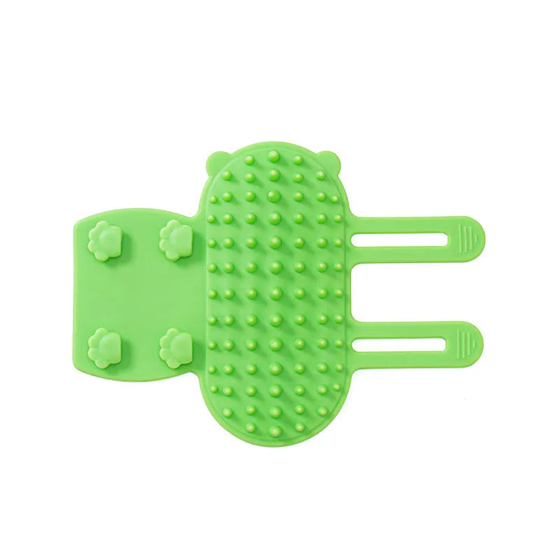 Silicone cat grooming comb with adjustable strap mounted on a table leg, shown in green.